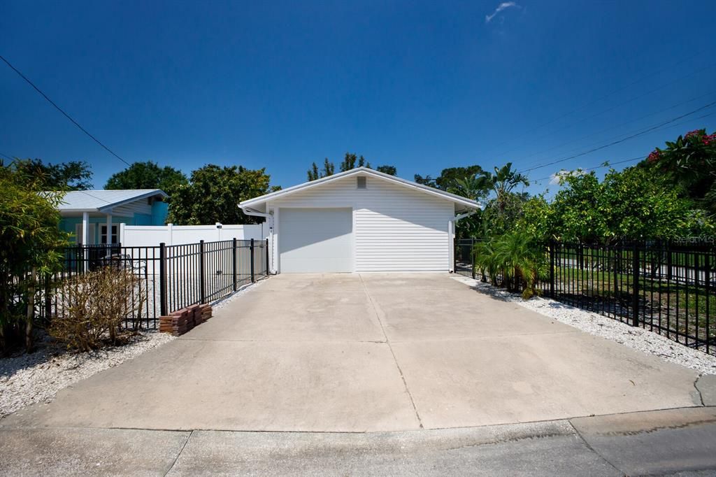 Driveway to the garage and view of other fenced yard sections.