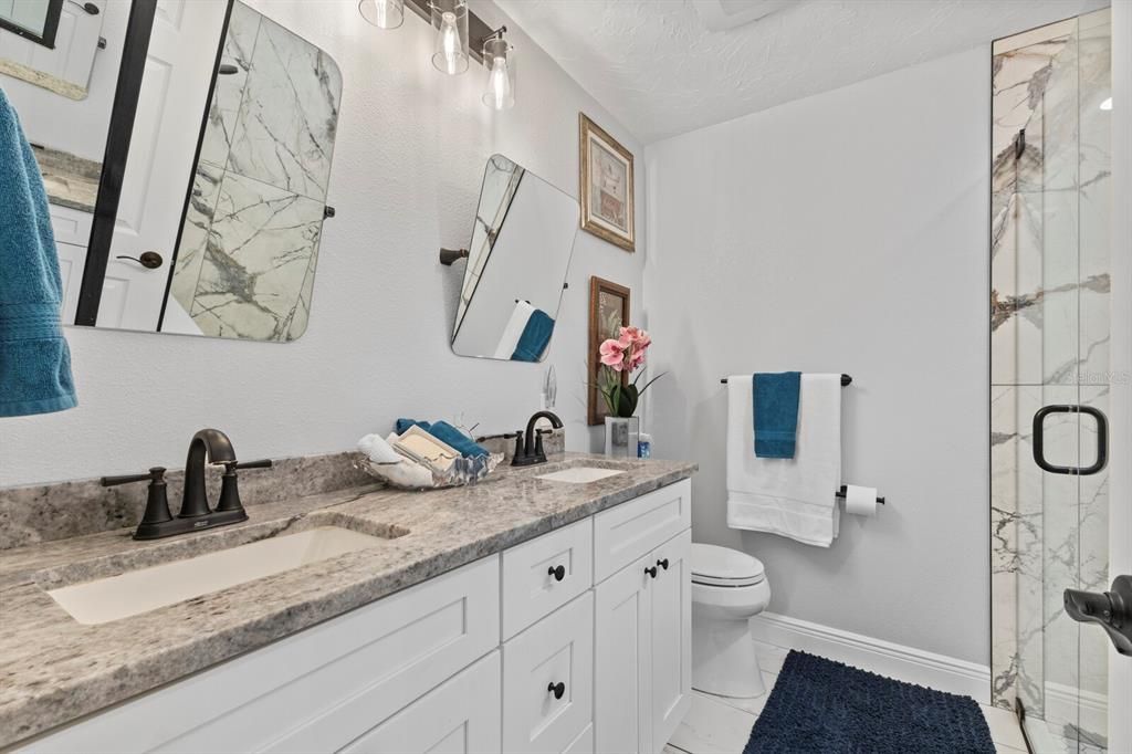 Primary bathroom with stone counters, a walk-in shower and lots of natural light.