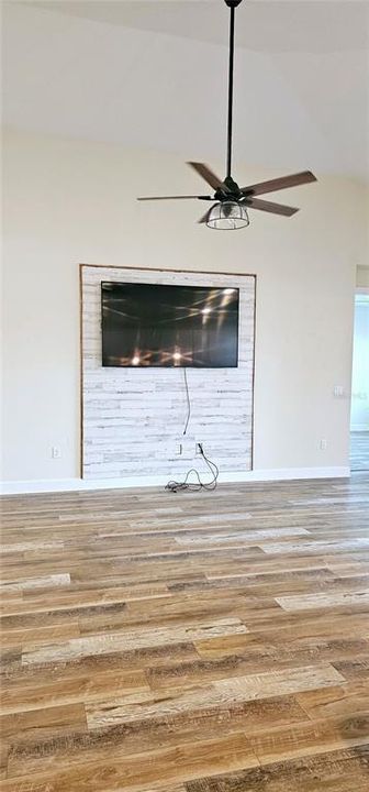 Open concept Great Room with vaulted ceiling with recessed lighting, ceiling fan, Luxury Vinyl flooring, and sliding doors leading to screened and paved Lanai.