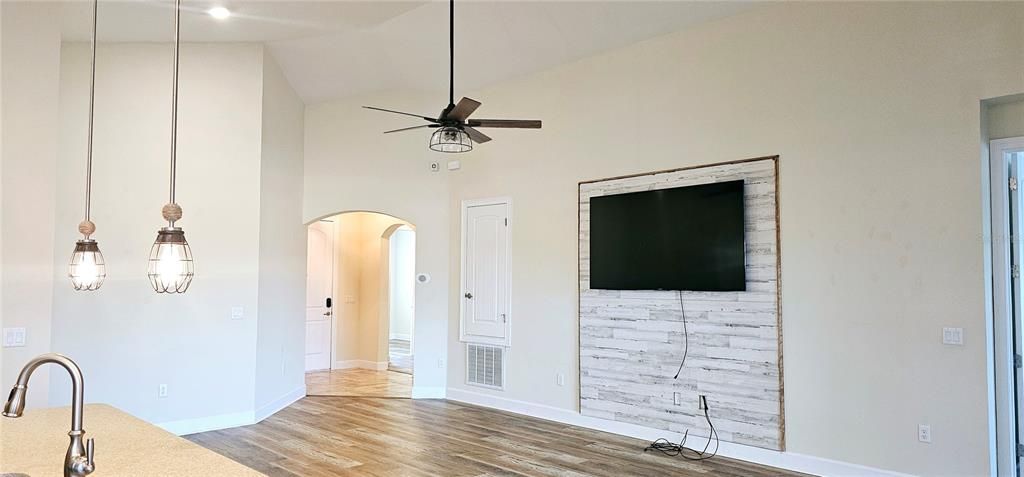 Open concept Great Room with vaulted ceiling with recessed lighting, ceiling fan, Luxury Vinyl flooring, and sliding doors leading to screened and paved Lanai.