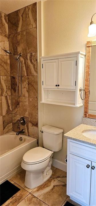 Guest Bathroom with porcelain tiles and tiled shower/tub combo, and vanity with Quartz counters.