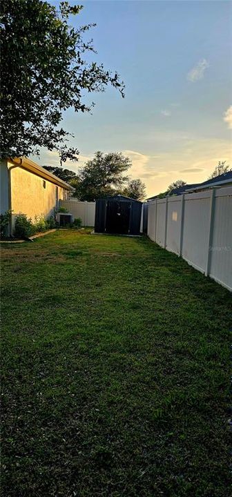 View of Left side of home and shed in fenced yard.