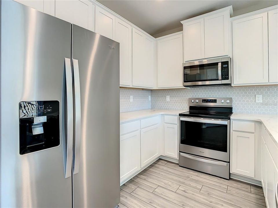 Kitchen that offers quartz countertops, solid wood cabinets, walk-in pantry, and stainless-steel appliances