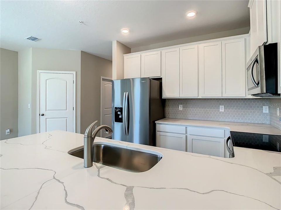 Kitchen that offers quartz countertops, solid wood cabinets, walk-in pantry, and stainless-steel appliances