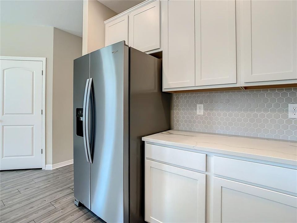 Kitchen that offers quartz countertops, solid wood cabinets, walk-in pantry, and stainless-steel appliances