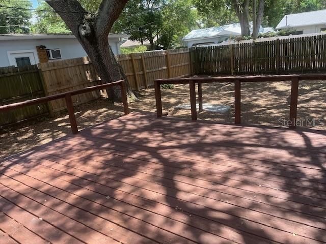 Wooden deck overlooks fenced backyard
