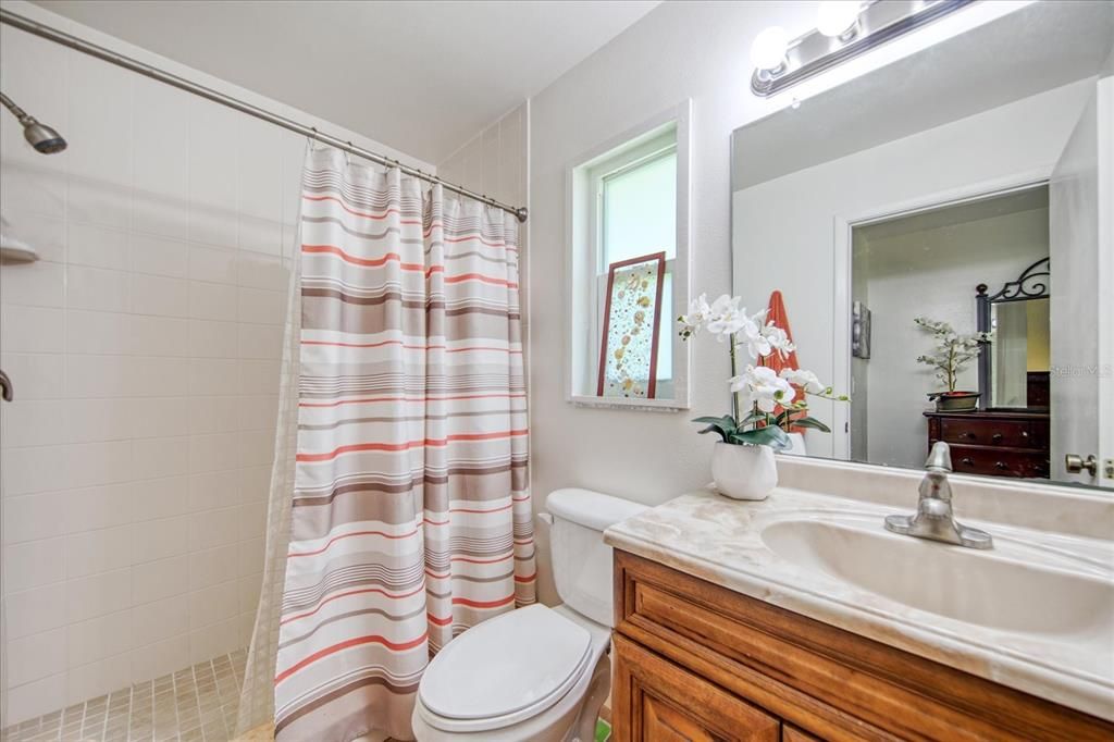 Lovely master bathroom with newer step-in shower, comfort commode, wood vanity & light fixture~