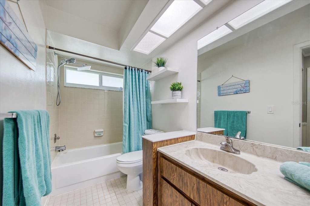 Hall bathroom with tub/shower, newer commode, rain shower head & window~