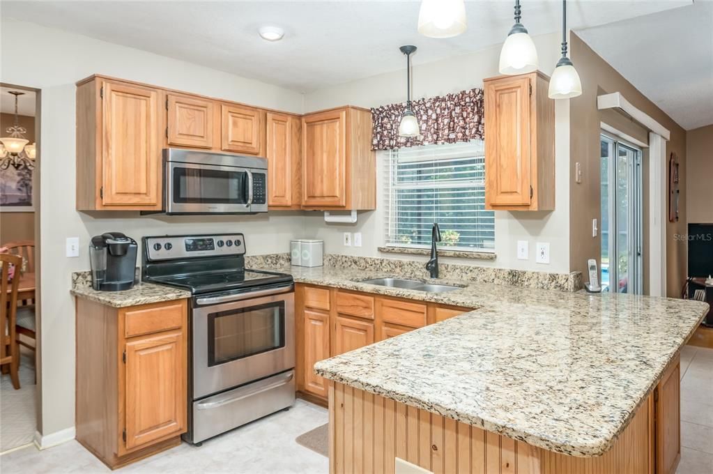 Kitchen - open to family room (right), next to dining room (left), and view of the pool over the kitchen sink