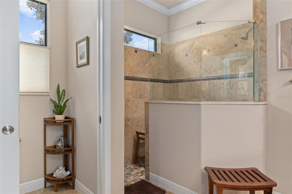 The easy walk-in shower features a partial glass window, and high fixed window to allow for natural light, while maintaining privacy. The opening on the left is the private Water Closet.