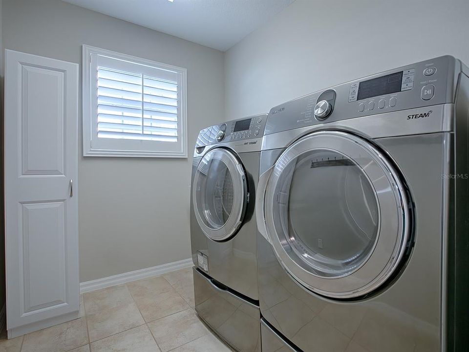 INSIDE LAUNDRY ROOM IS OFF THE KITCHEN WITH PLANTATION SHUTTERS AND FRONT LOAD WASHER AND DRYER THAT DO CONVEY WITH THE HOME.