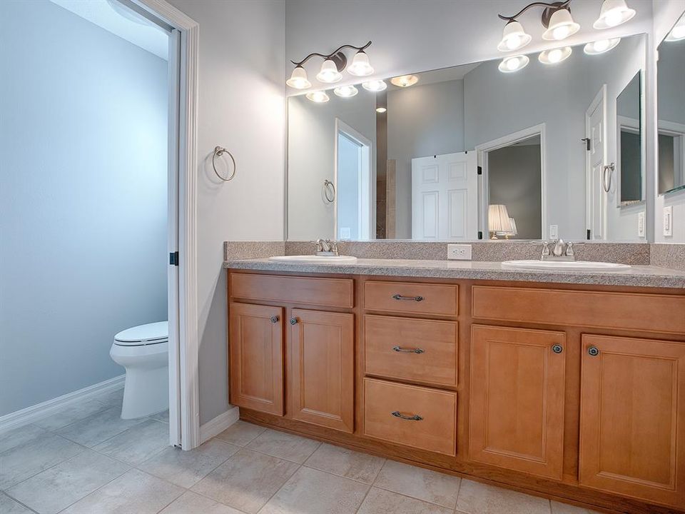 PRIMARY BATH WITH TILE FLOORING AND POCKET DOOR THAT LEADS TO THE SEPARATE TOILET ROOM.