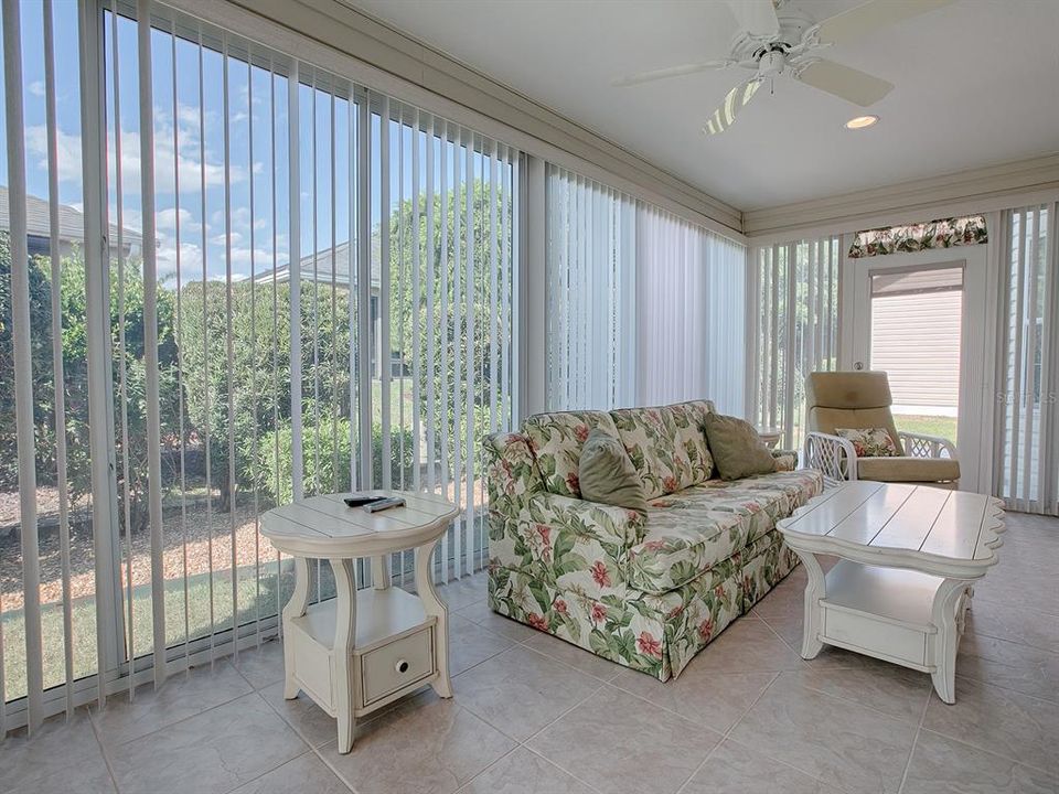 ENCLOSED LANAI WITH TILE FLOORING AND PRIVACY LANDSCAPING.