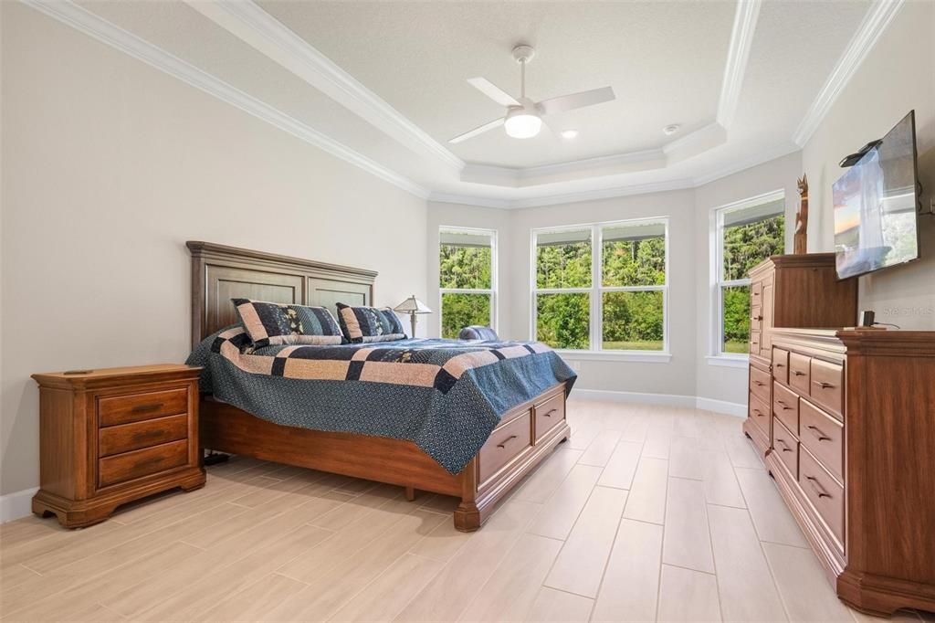 Step into the gorgeous primary bedroom, filled with upgrades: a custom tray ceiling, crown molding, and bay windows.