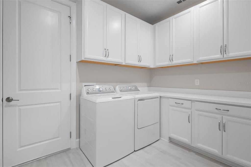 The massive laundry room has upgraded upper and lower cabinets as well as a cute 'drop nook' near the garage door.