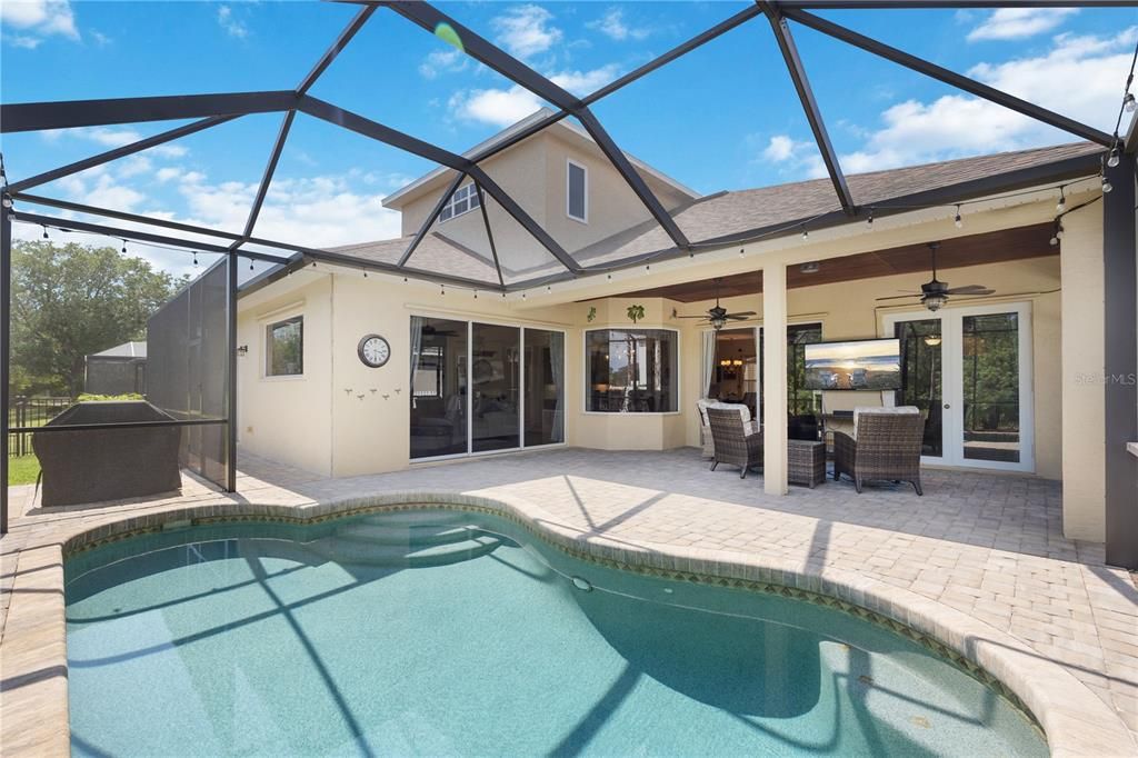 Heated saltwater pool, brick paver, screened-in lanai, pocket sliders, and French doors surrounding the pool, with side entrance leading to fourth bathroom.