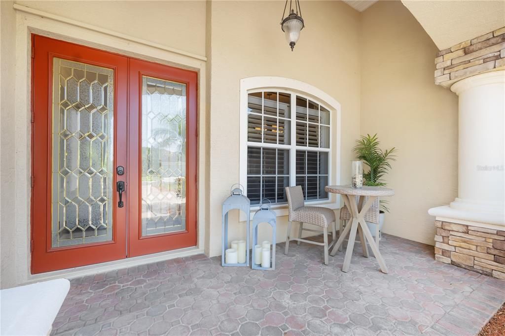 Covered paver front porch spacious enough for table and chairs to lounge in.