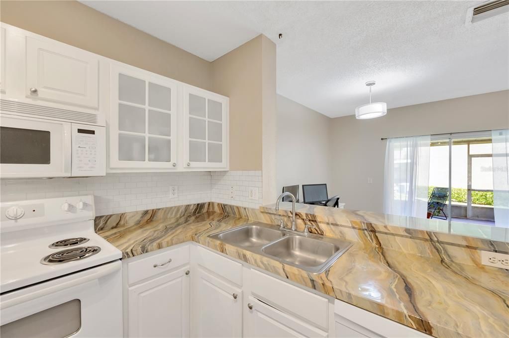 The kitchen features freshly painted white cabinetry with stylish glass inserts that obscure the contents inside, upgraded appliances, breakfast bar and a closet pantry for extra storage.