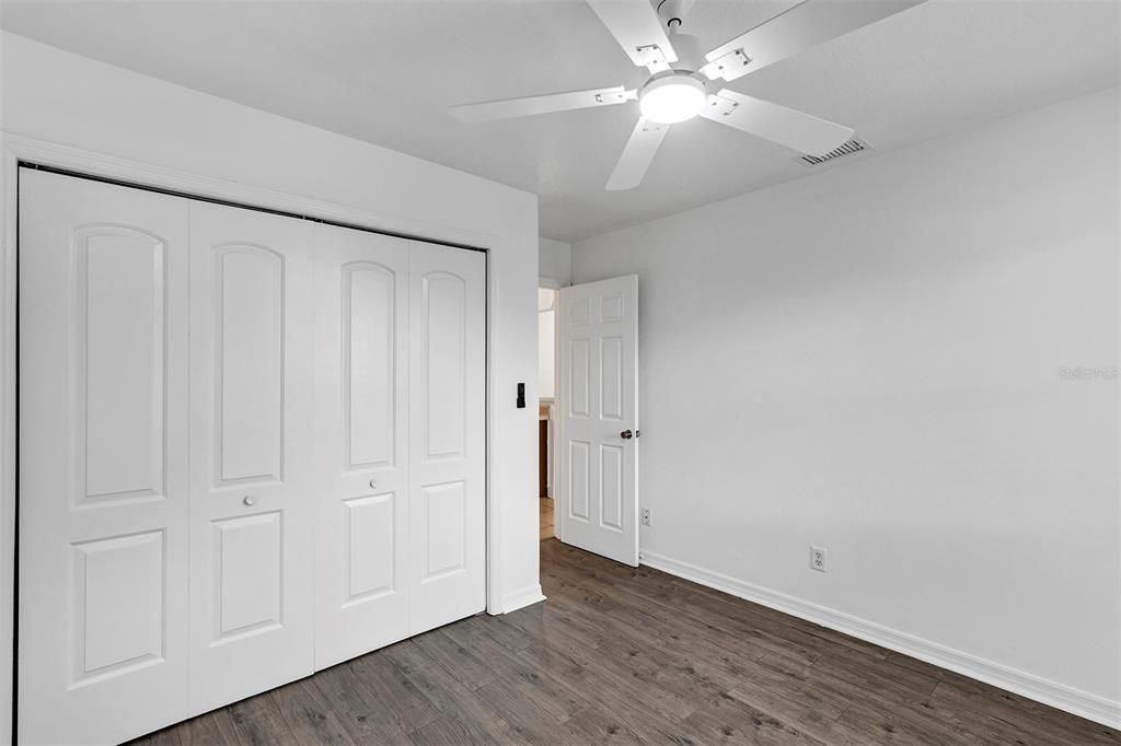 2nd room with long closet, vinyl luxury and ceiling fan.