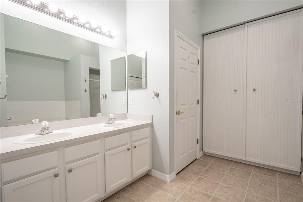 The primary bath features ceramic tile flooring, a mirrored vanity with storage and dual sinks.