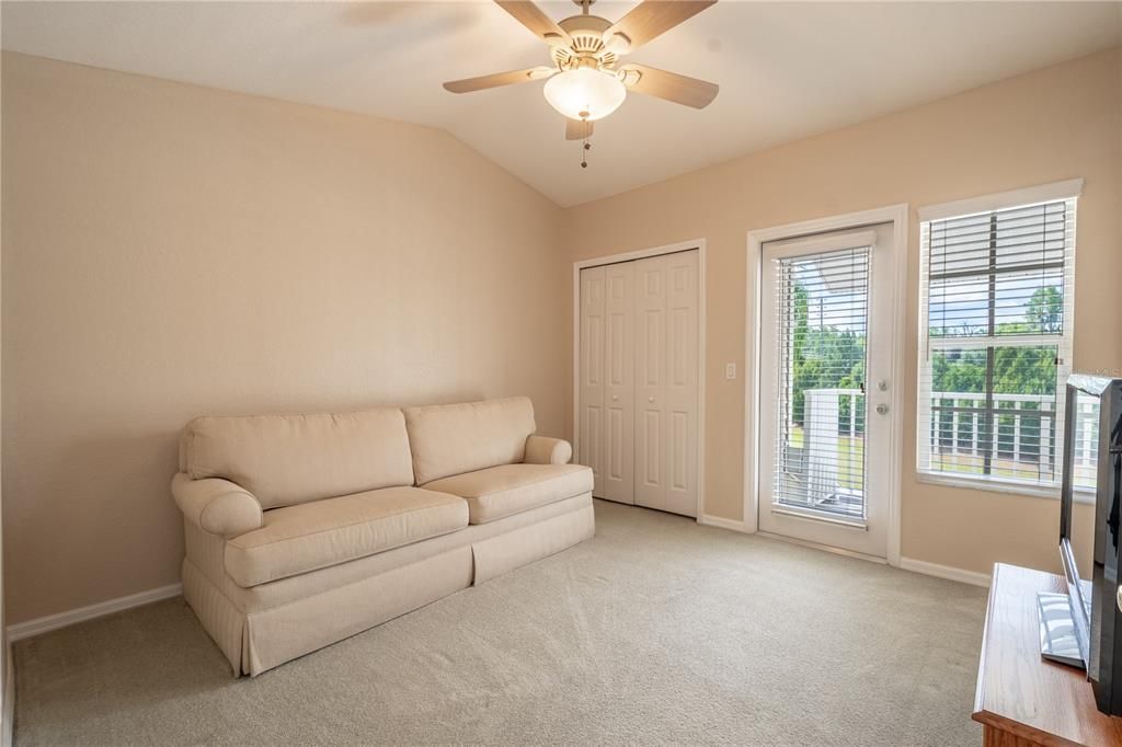 Bedroom 3 mirrors bedroom 2 with plush carpet, neutral tones, a ceiling fan, built in closet and French door to the shared balcony.