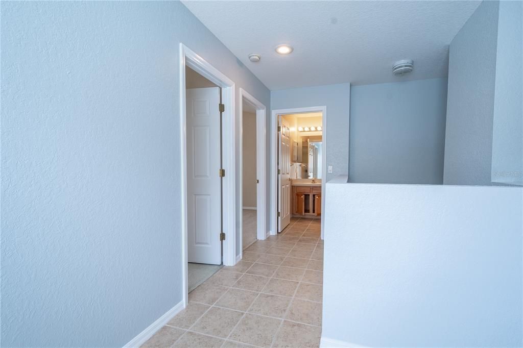 Bedroom 2 features plush carpet, neutral tones, a ceiling fan, built in closet and French door to the balcony.