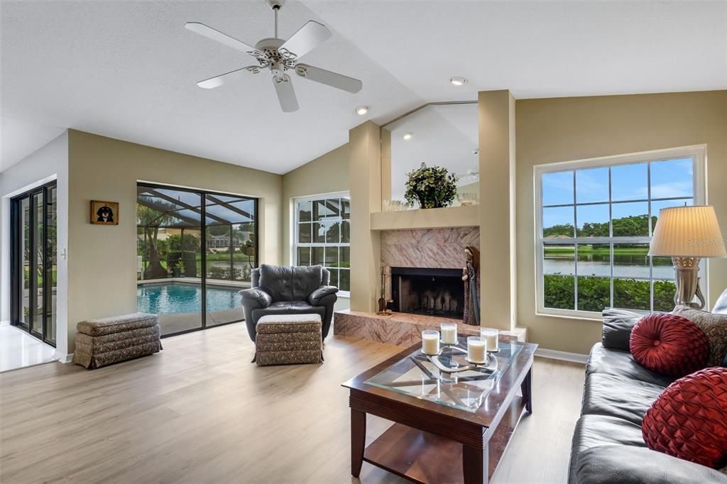 The family room features vaulted ceilings, wood burning fireplace , luxury vinyl plank flooring and a wonderful view of the Lake