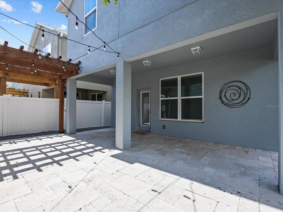 Partially covered Lanai with travertine floors and bistro lights and quaint trellis. Add a fire pit and lounge chairs for your enjoyment