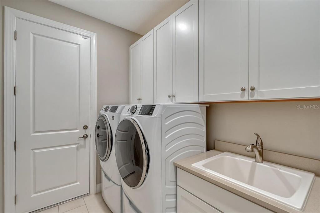 The laundry room is fully equipped with GE front-loading washer/dryer, quartz counter tops, sink, and upper cabinets for additional storage.