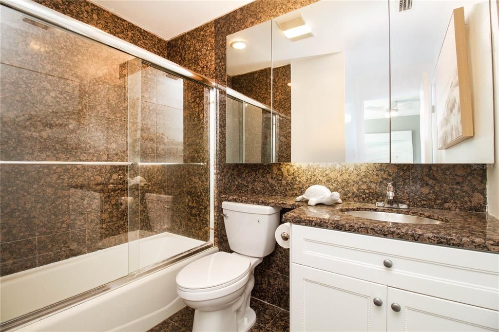 2nd floor primary bedroom, comfortable tub/shower combo with lots of storage including a linen closet, and floor to ceiling granite (Please note: Shower glass doors have been removed and replaced with shower curtain)