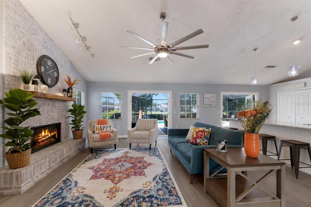 Large great room featuring a natural gas fireplace surrounded by floor to ceiling whitewashed brick with a large mantle and hearth.