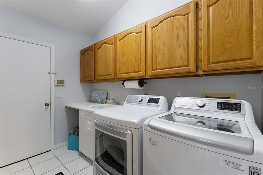 Interior laundry room with sink and storage with door to 2 car garage