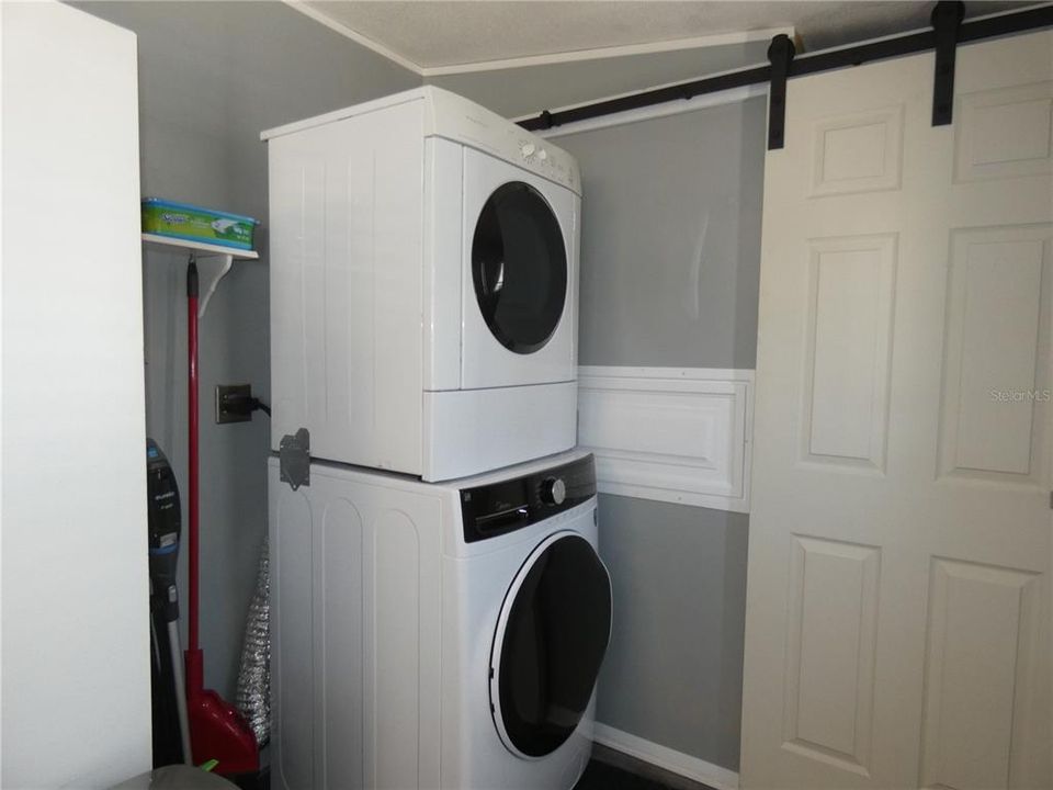 Inside laundry with new stackable front load washer and dryer.