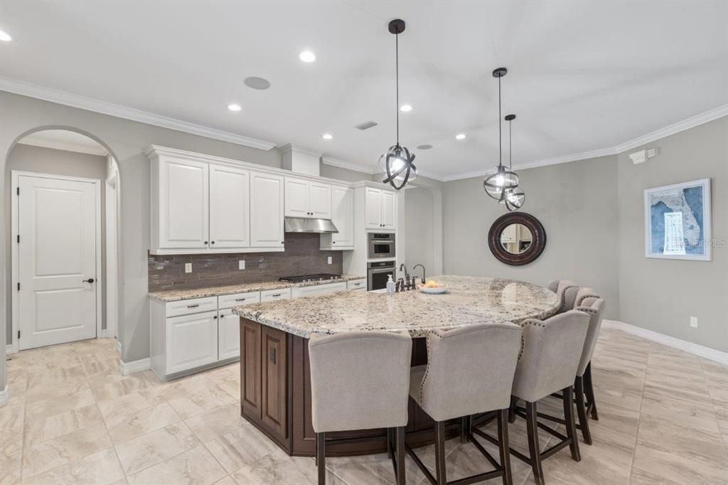 Gourmet kitchen featuring built-in stainless steel kitchen aid appliances, custom two tone cabinetry, a massive island with 3" bezzle, and granite countertops.