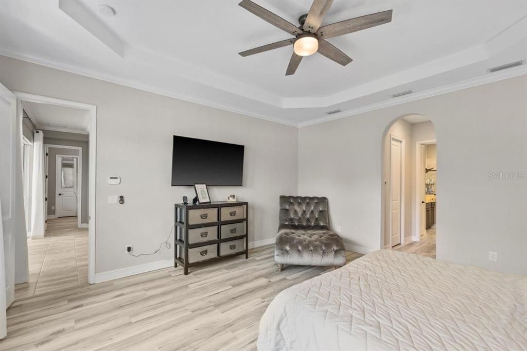 Owners suite featuring a tray ceiling, wainscotting, dual walk-in closets, and an ensuite bathroom.