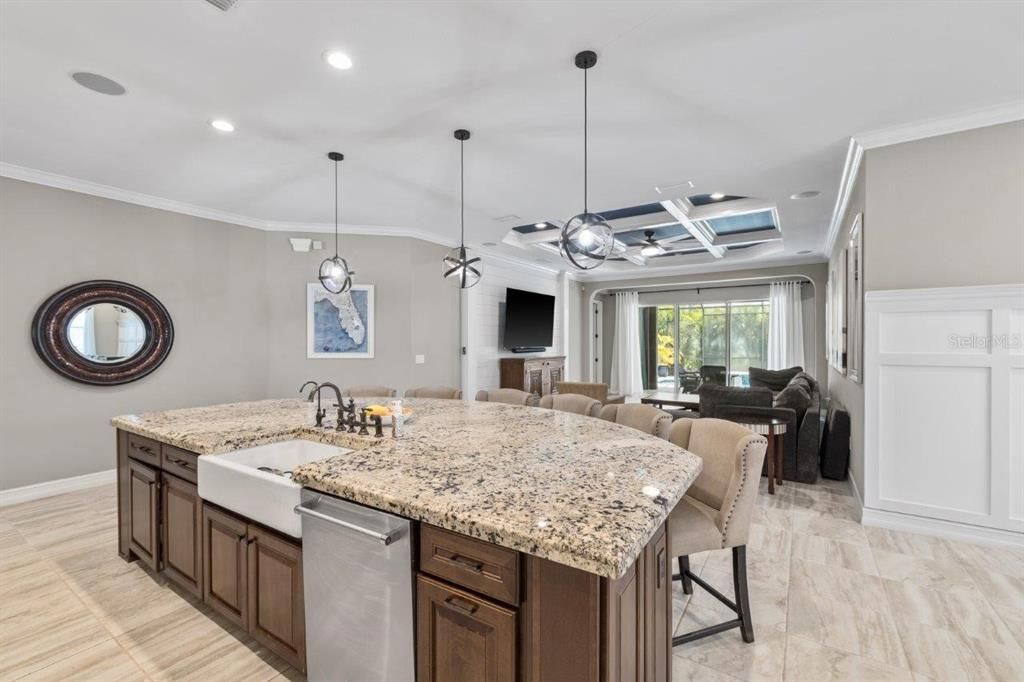 Gourmet kitchen featuring built-in stainless steel kitchen aid appliances, custom two tone cabinetry, a massive island with 3" bezzle, and granite countertops.