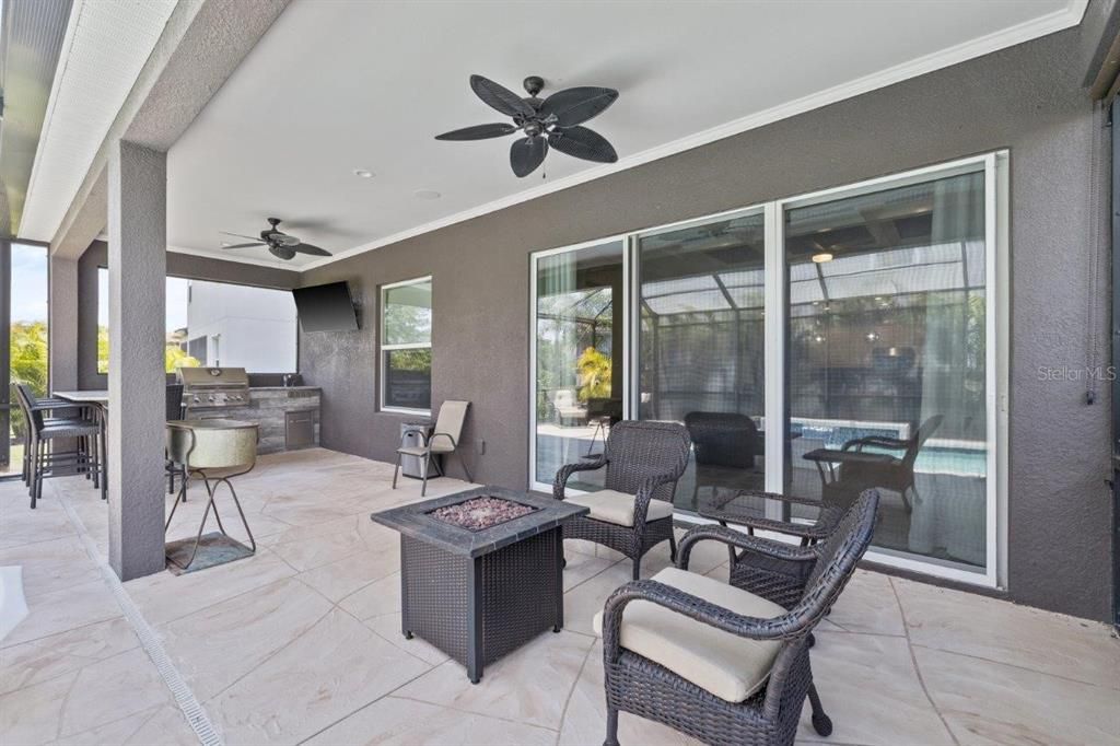 Extended screened-in lanai featuring a heated pool with a sun shelf, and full outdoor kitchen.