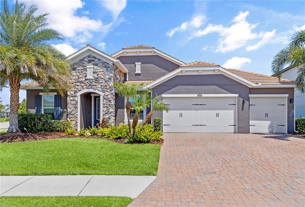 Stunning stacked stone front elevation showing the extended 3 car garage, and extended driveway.