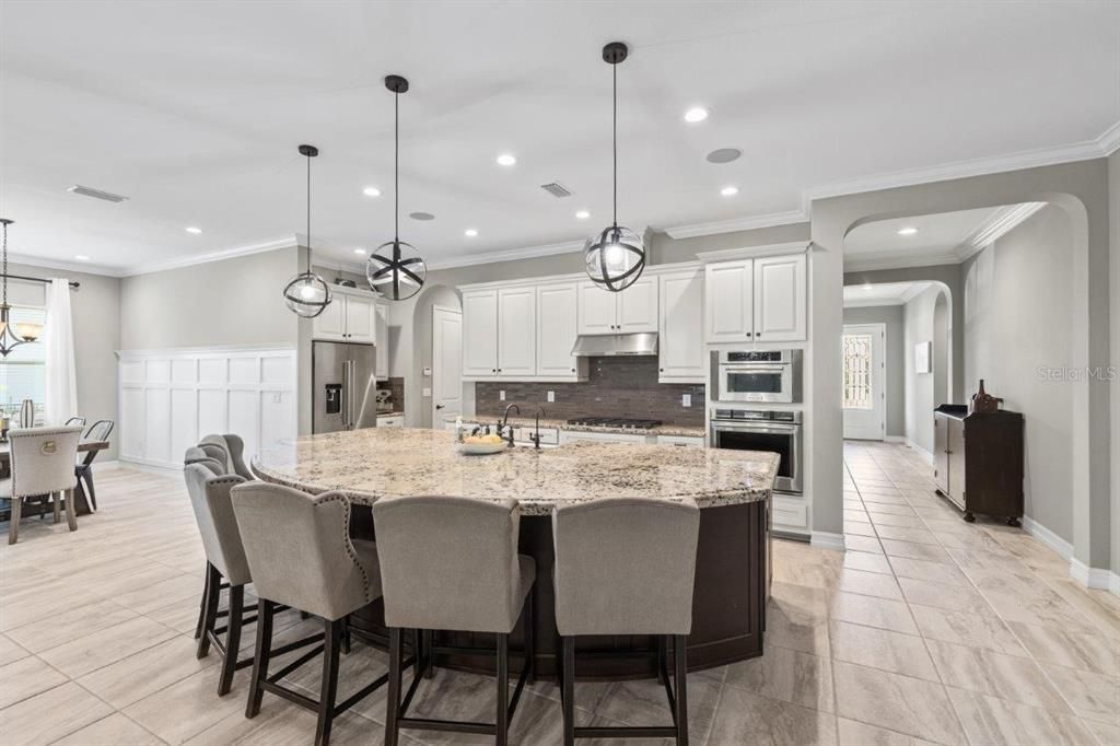 Gourmet kitchen featuring built-in stainless steel kitchen aid appliances, custom two tone cabinetry, a massive island with 3" bezzle, and granite countertops.