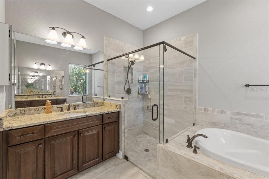 Owners ensuite bathroom featuring dual vanities, a garden tub, and a frameless glass enclosed shower.