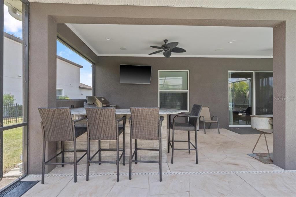 Extended screened-in lanai featuring a heated pool with a sun shelf, and full outdoor kitchen.