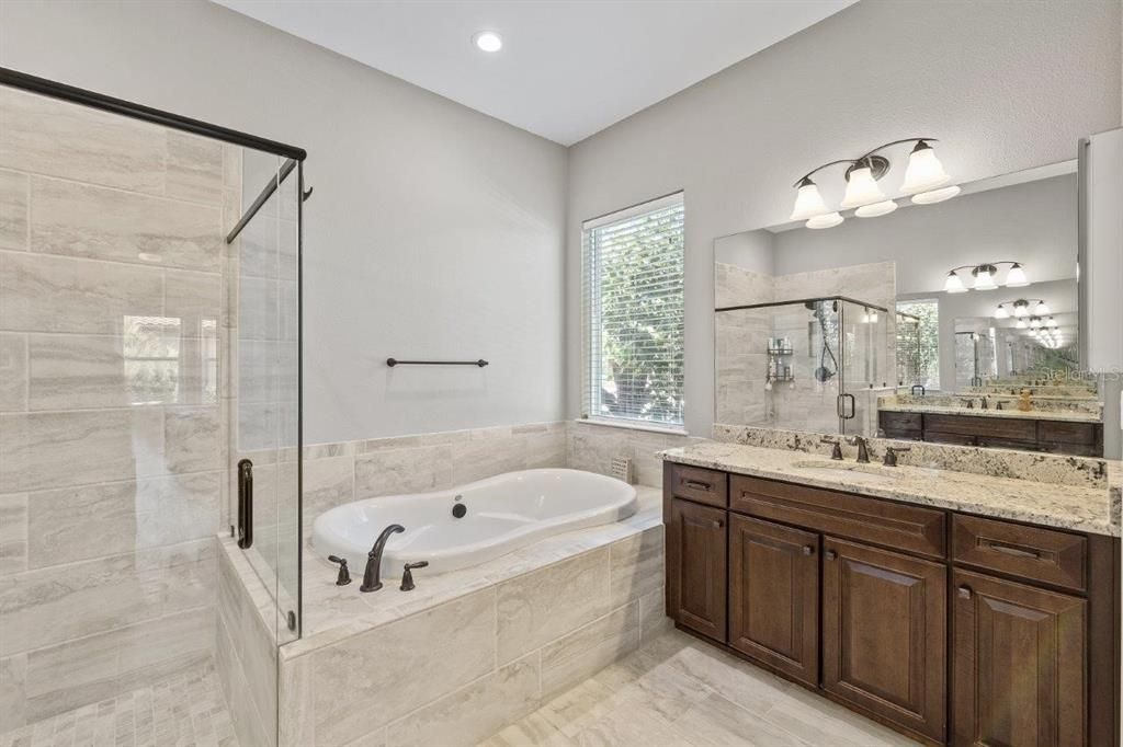 Owners ensuite bathroom featuring dual vanities, a garden tub, and a frameless glass enclosed shower.