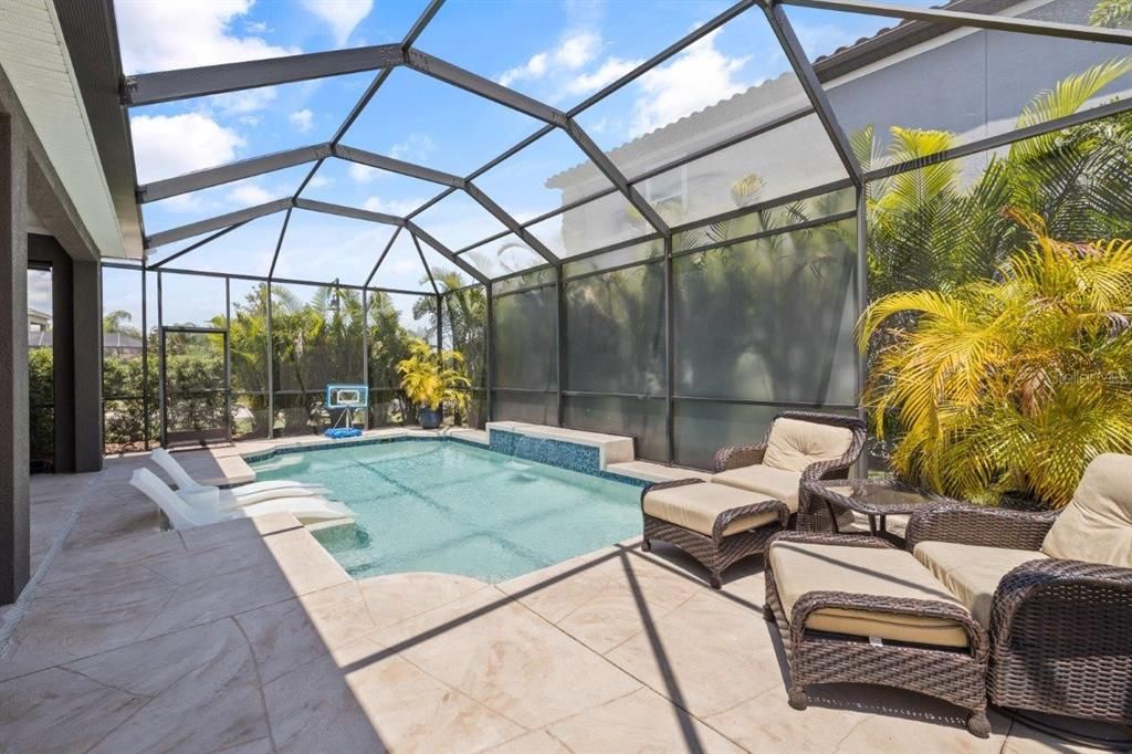 Extended screened-in lanai featuring a heated pool with a sun shelf, and full outdoor kitchen.