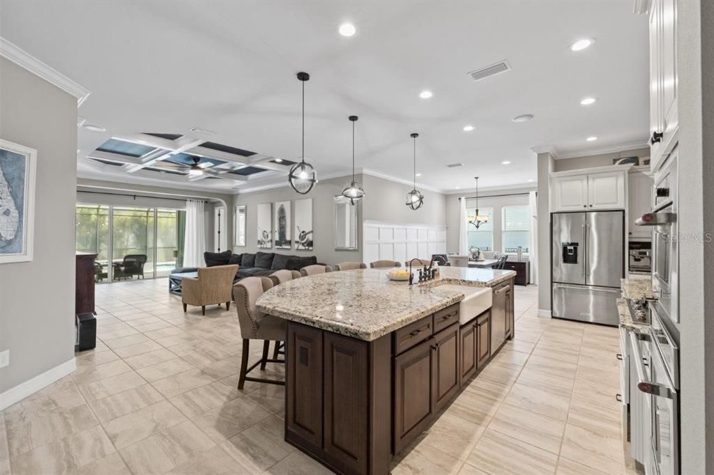 Gourmet kitchen featuring built-in stainless steel kitchen aid appliances, custom two tone cabinetry, a massive island with 3" bezzle, and granite countertops.