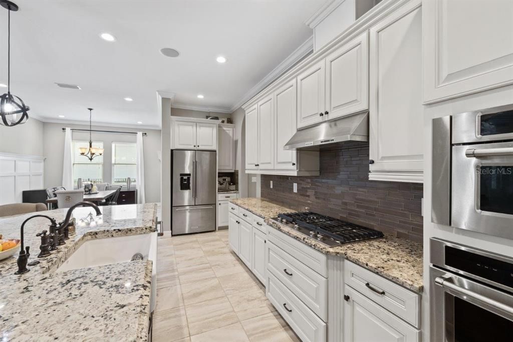 Gourmet kitchen featuring built-in stainless steel kitchen aid appliances, custom two tone cabinetry, a massive island with 3" bezzle, and granite countertops.