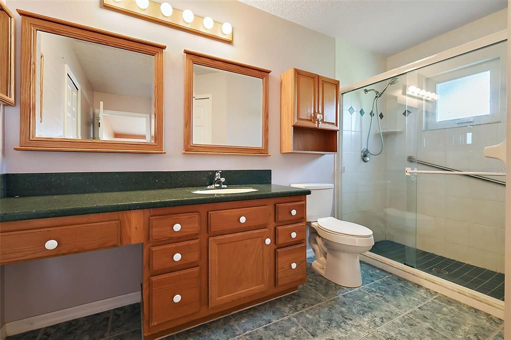 En-suite bath with tile shower and makeup counter space