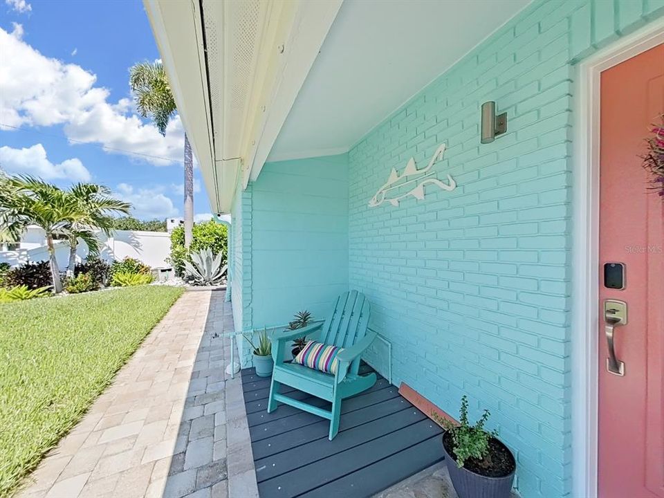 Your front yard and porch exude coastal charm! Fresh paint in vibrant colors, tropical landscape, and neutral brick pavers add to the coastal flair!