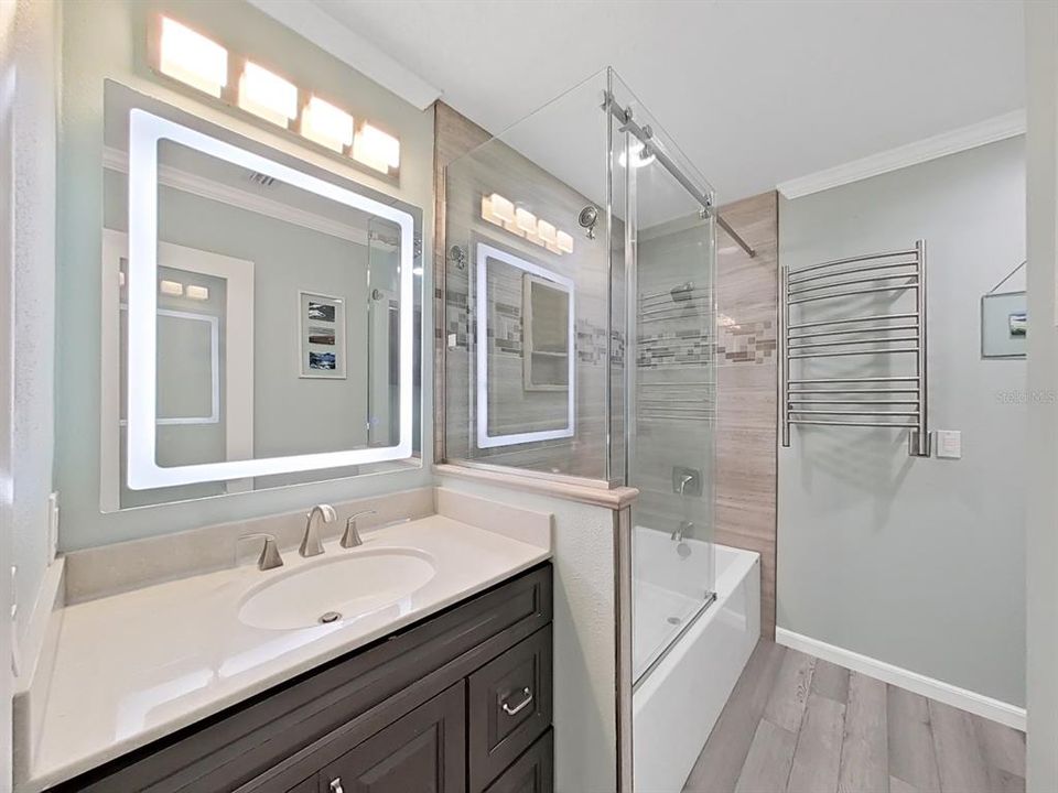 Modern Primary Bathroom with illuminated mirror & tub/shower with frameless glass.