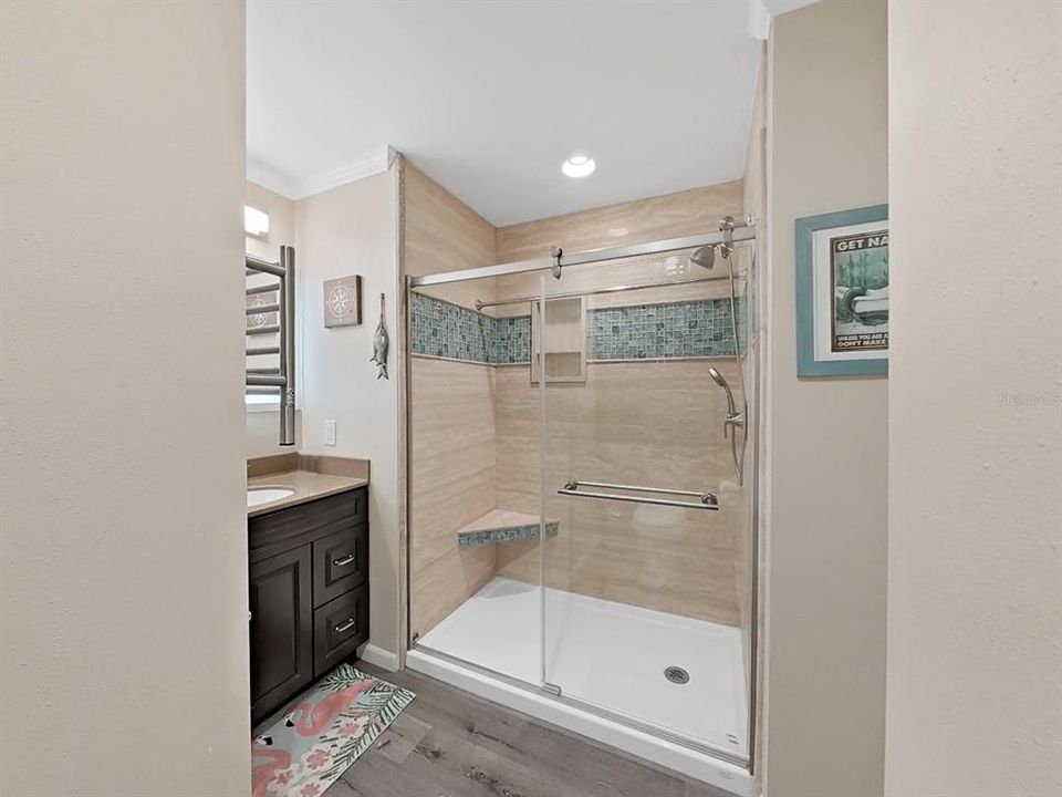 Bathroom 2. Modern touches like crown molding, mounted towel warmer, step-in shower with tile, corner bench, and glass doors.