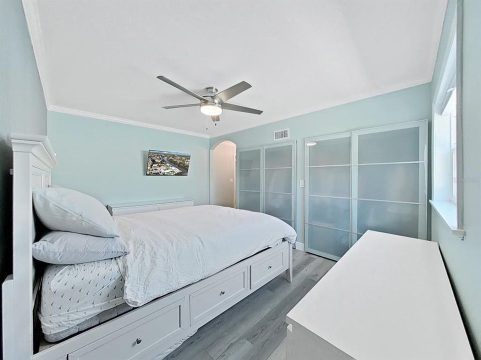 Primary Suite with Glass Sliding Wardrobe Doors, Crown Molding, Ceiling fan, and private En Suite Bathroom.